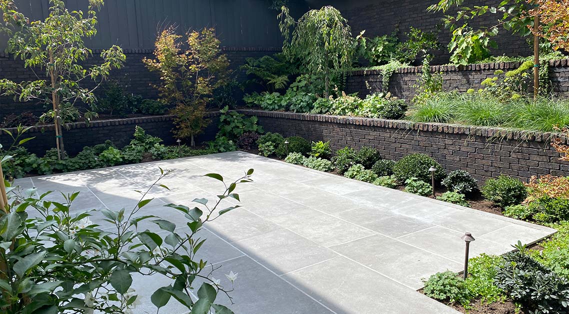 paved back yard with terraced brick walls featuring built-in planter beds