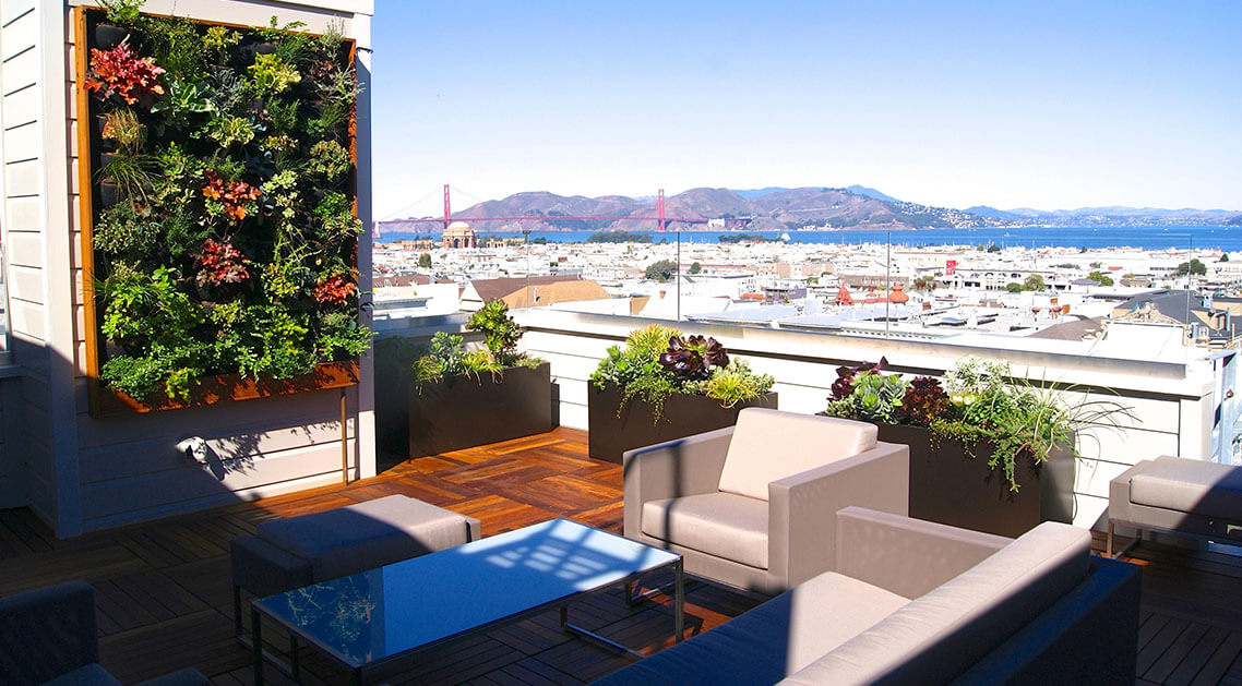 rooftop terrace featuring outdoor seating area, large living plant wall installation, and panoramic view of San Francisco marina and Golden Gate Bridge.