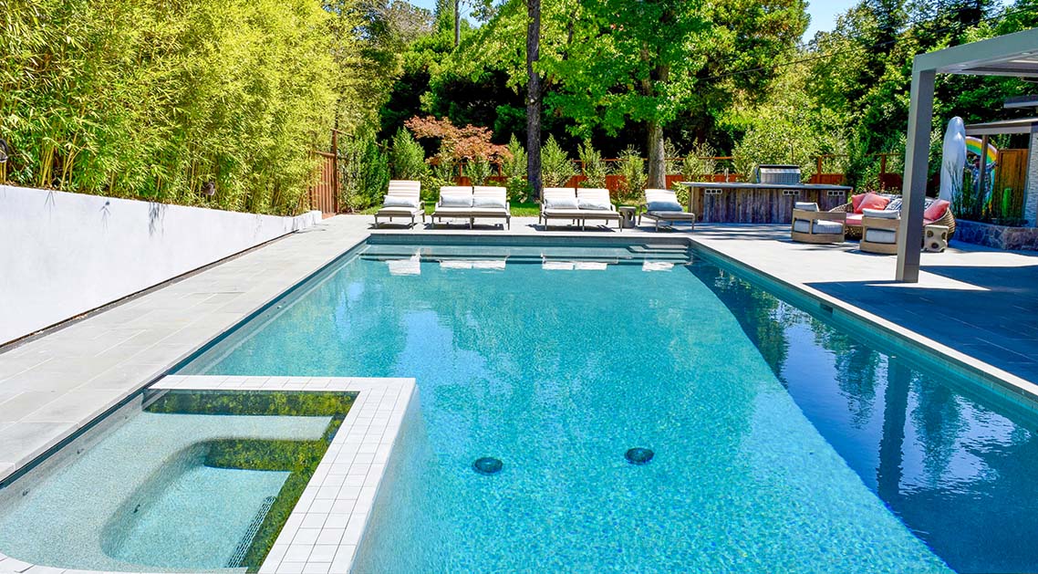 Paved back yard pool with seating and bamboo wall