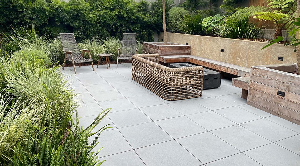 paved back yard with outdoor furniture and plants